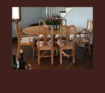 handmade pedestal dining table with oval top and brass lion's paw casters in tiger maple